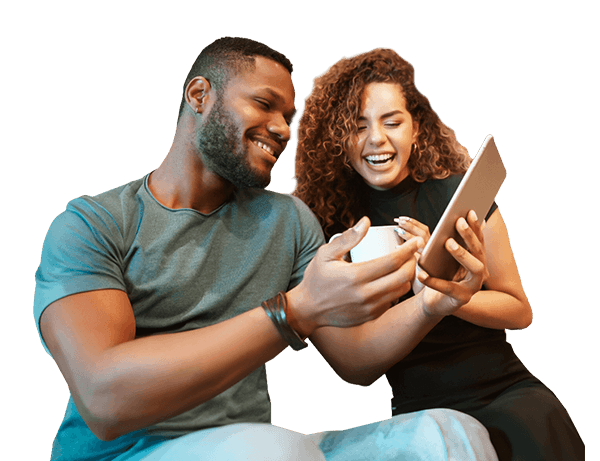 A happy couple enjoying together while using a tablet or smartphone in a cozy setting.